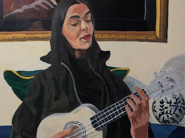 Self-portrait by Prachi. She is playing a ukelele and sitting on a couch. Behind her is a large painting of a person holding a flower.