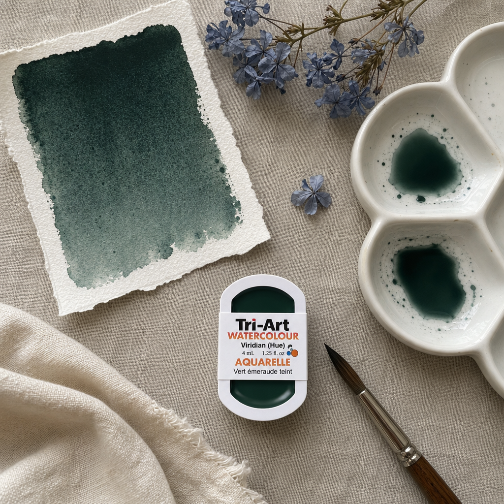 Tri-Art Watercolour pan in Viridian (Hue) with dark teal swatch, ceramic palette, and dried plumbago on grey linen