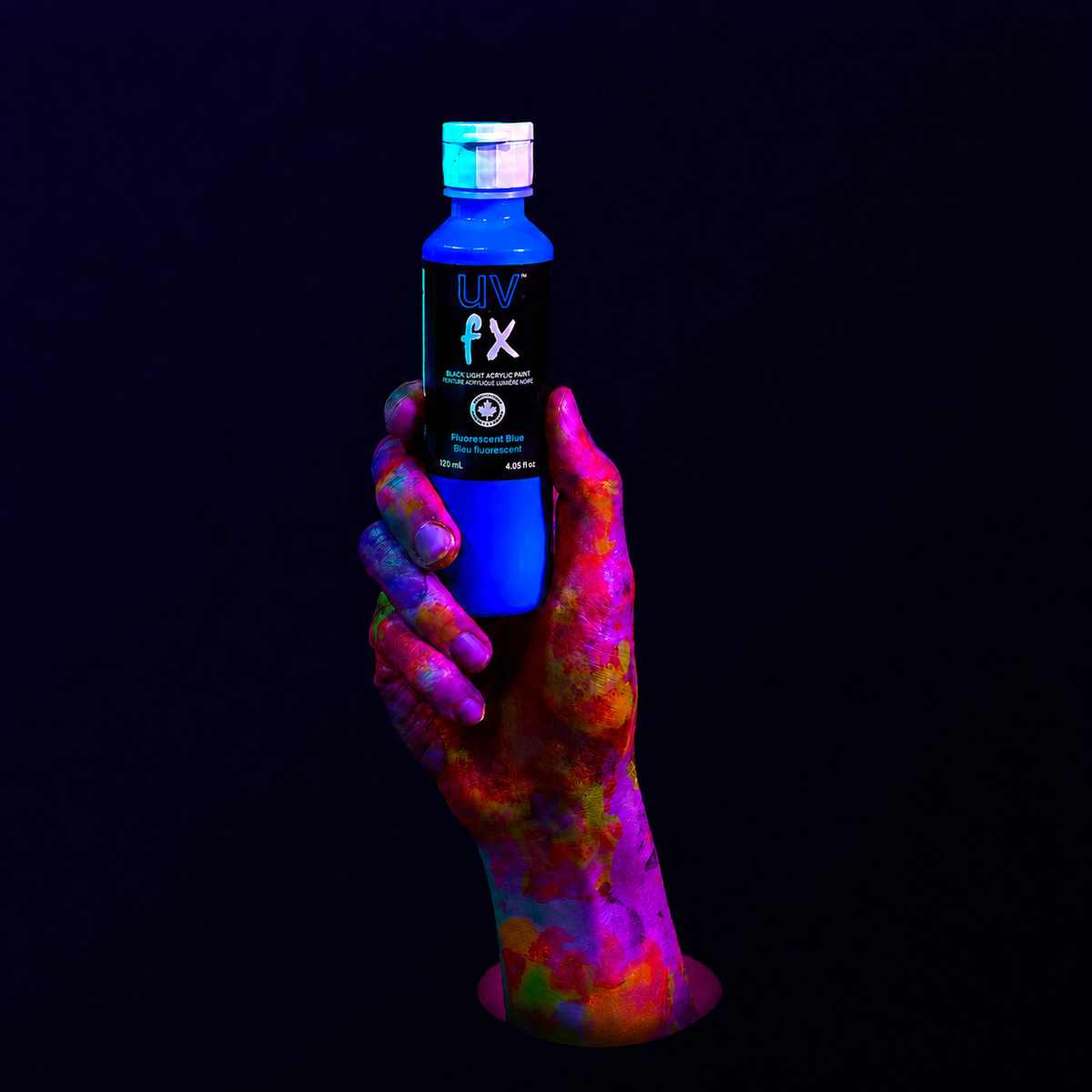 Hand holding a bottle of UV FX under black light on a dark background