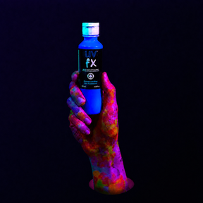 Hand holding a bottle of UV FX under black light on a dark background