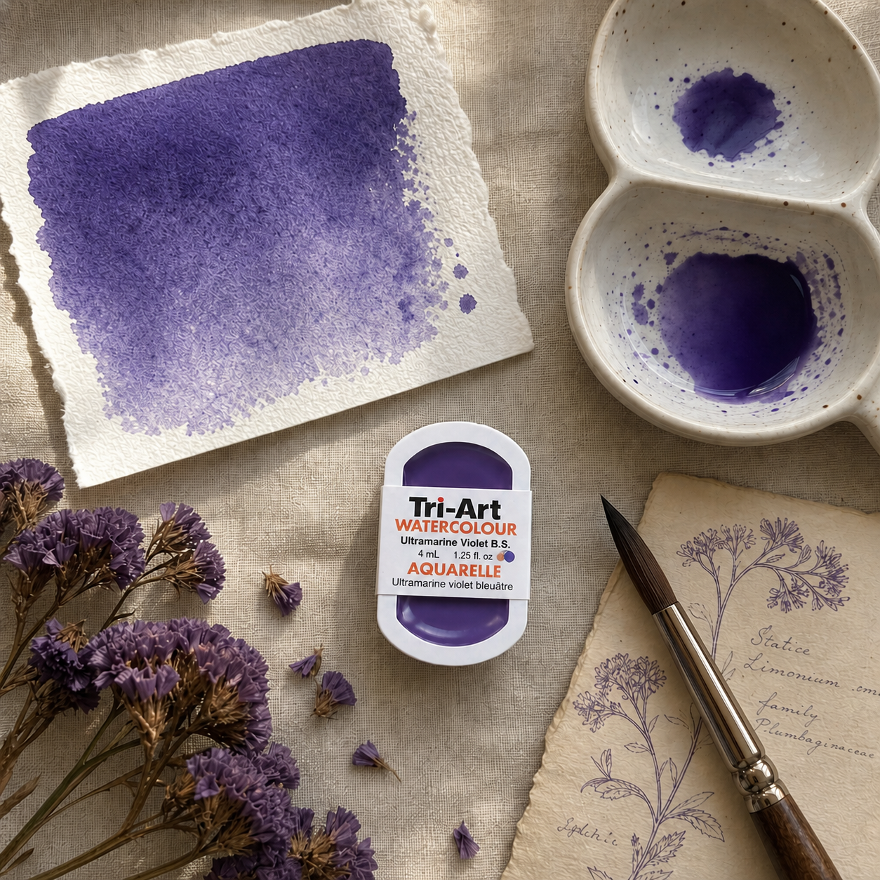 Tri-Art watercolor paint with a swatch on paper, brush, and floral elements on a textured surface